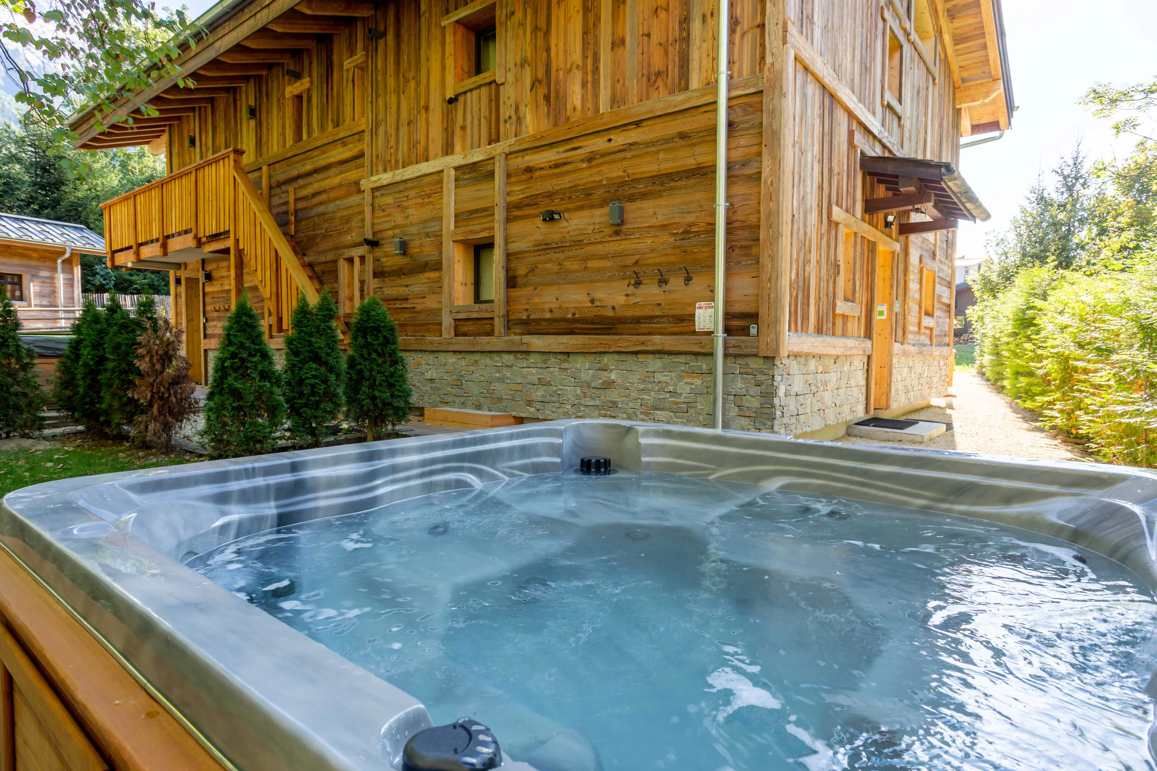Bain à remous dans le jardin d'un chalet en bois à Chamonix, abrité par des conifères