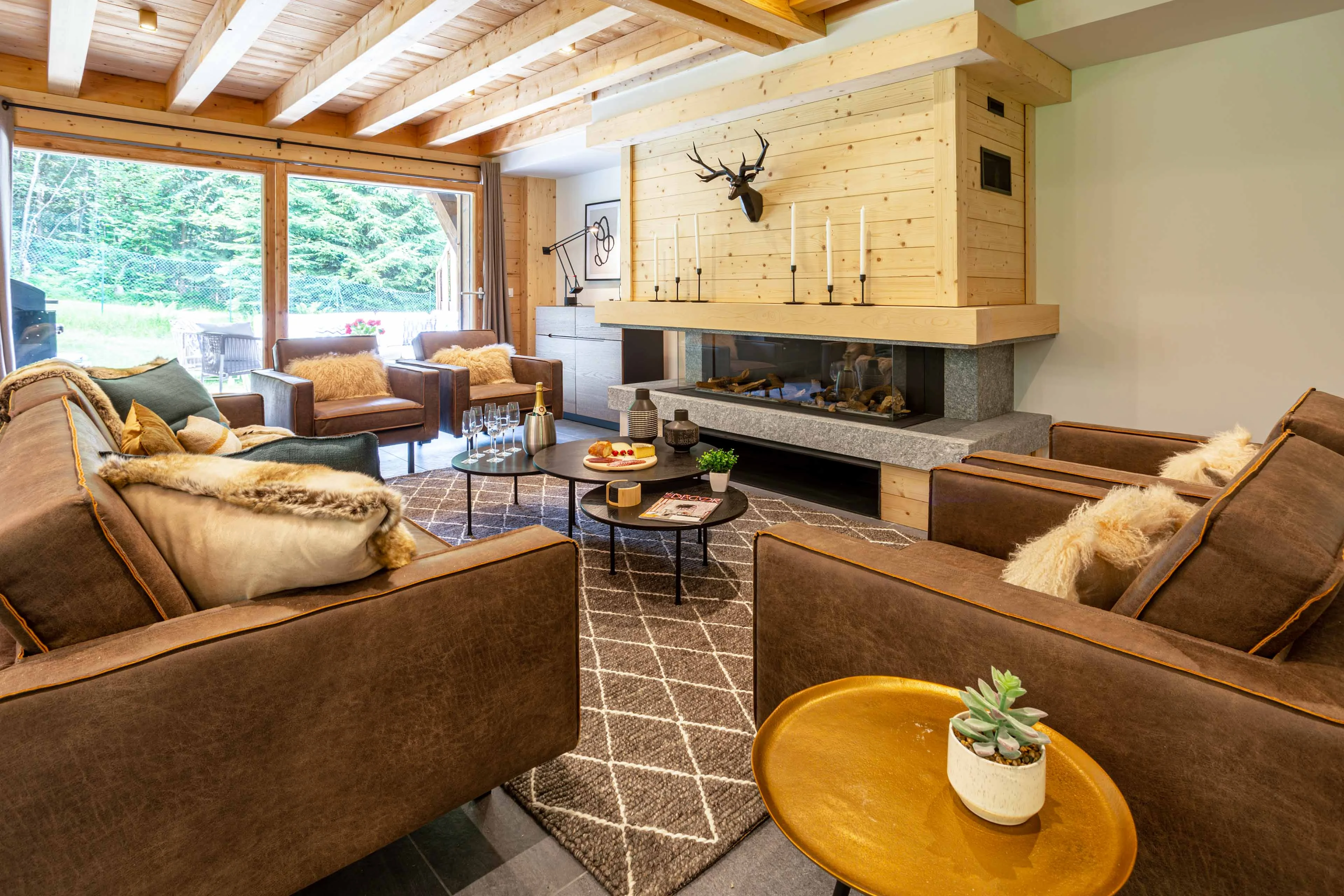 Open plan chalet living room in Chamonix with a long fireplace and leather armchairs