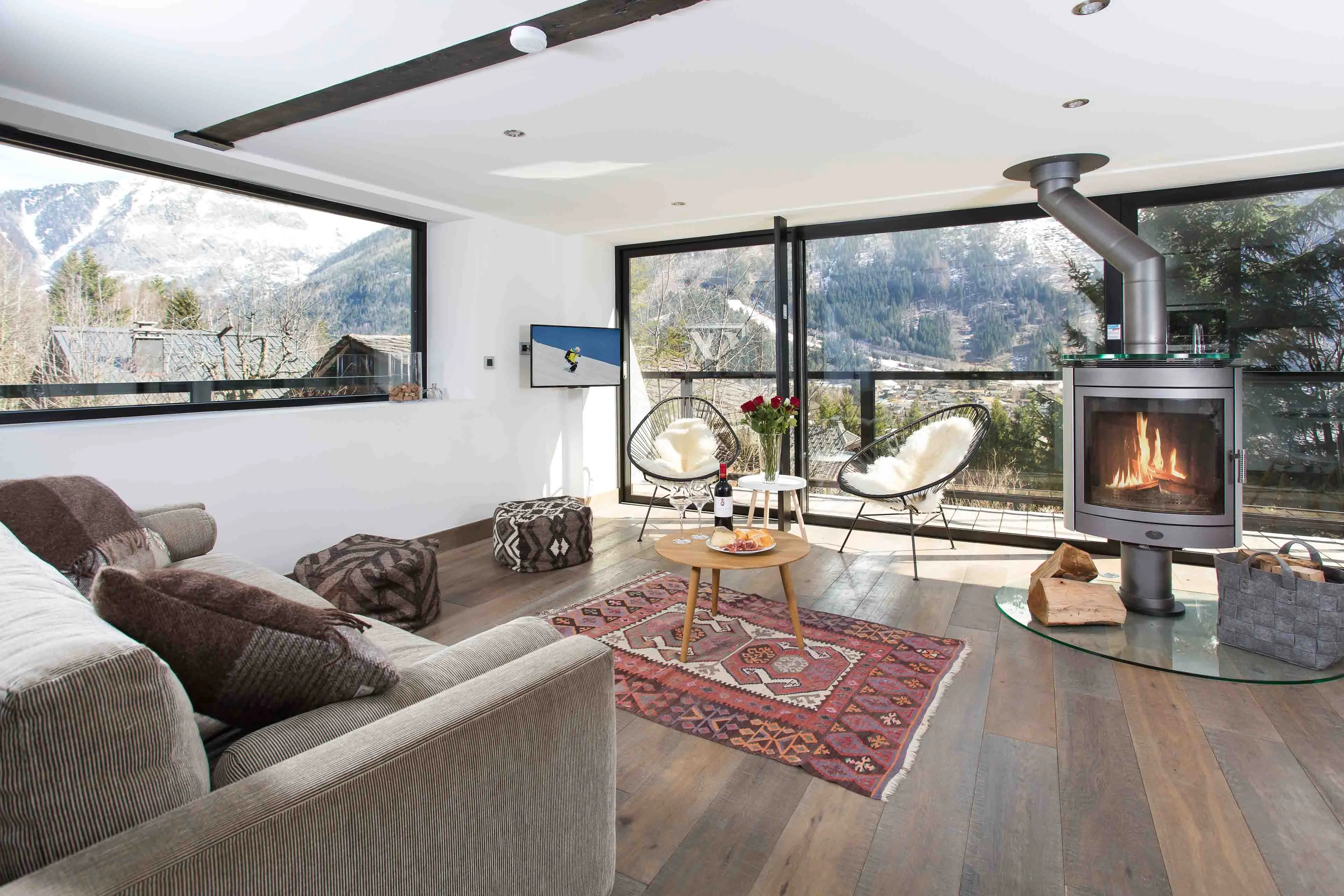 Salon avec poêle à bois et baies vitrées donnant sur les montagnes à Chamonix