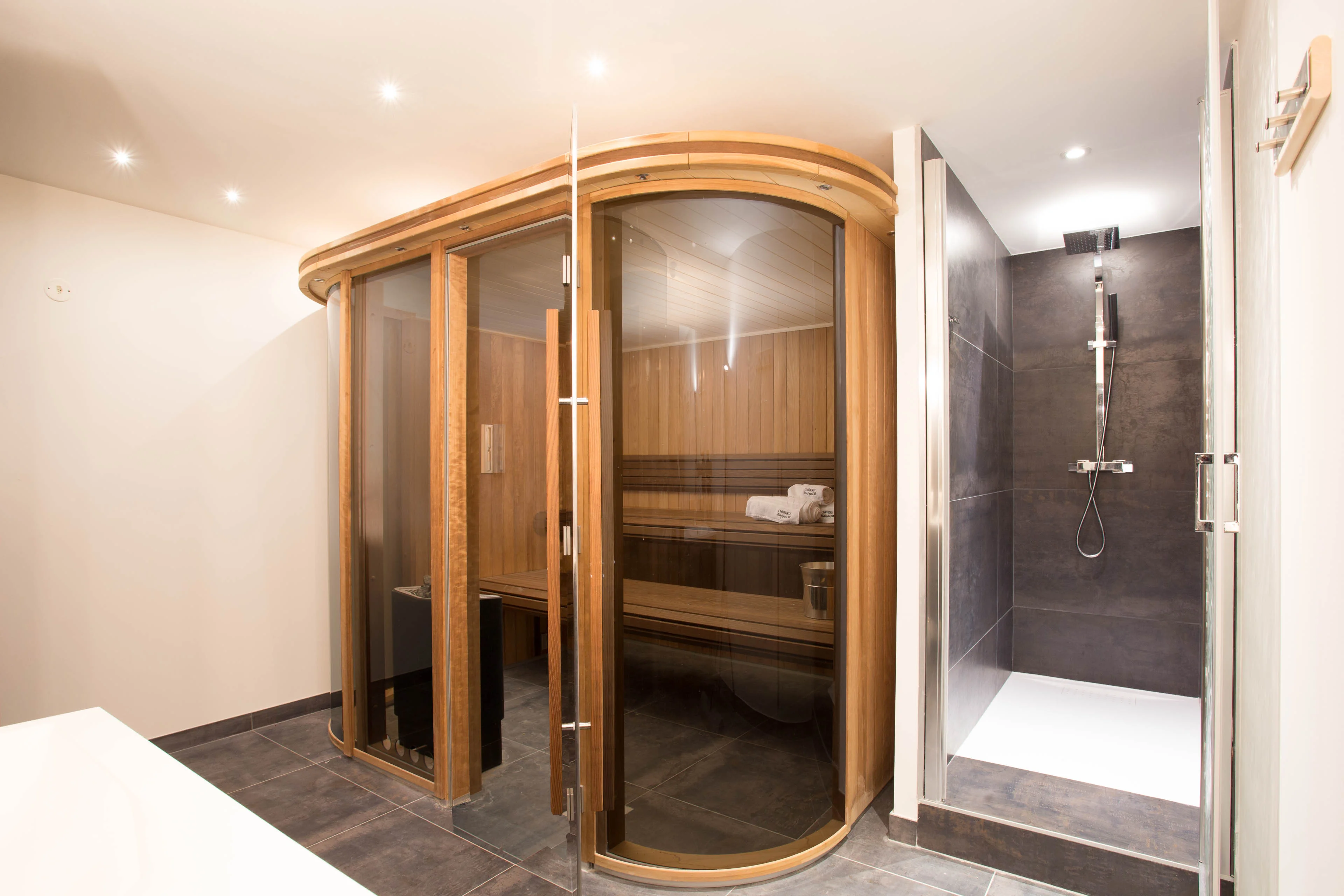 Sauna en verre incurvé à côté d'une douche à l'italienne dans un chalet à Chamonix