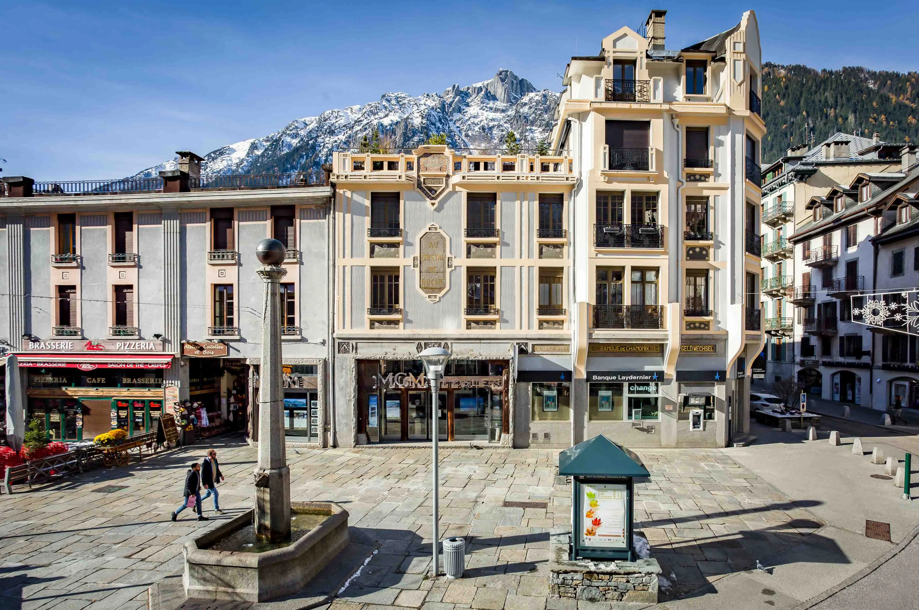 Place au centre de Chamonix avec fontaine en pierre et commerces au pied des Aiguilles Rouges