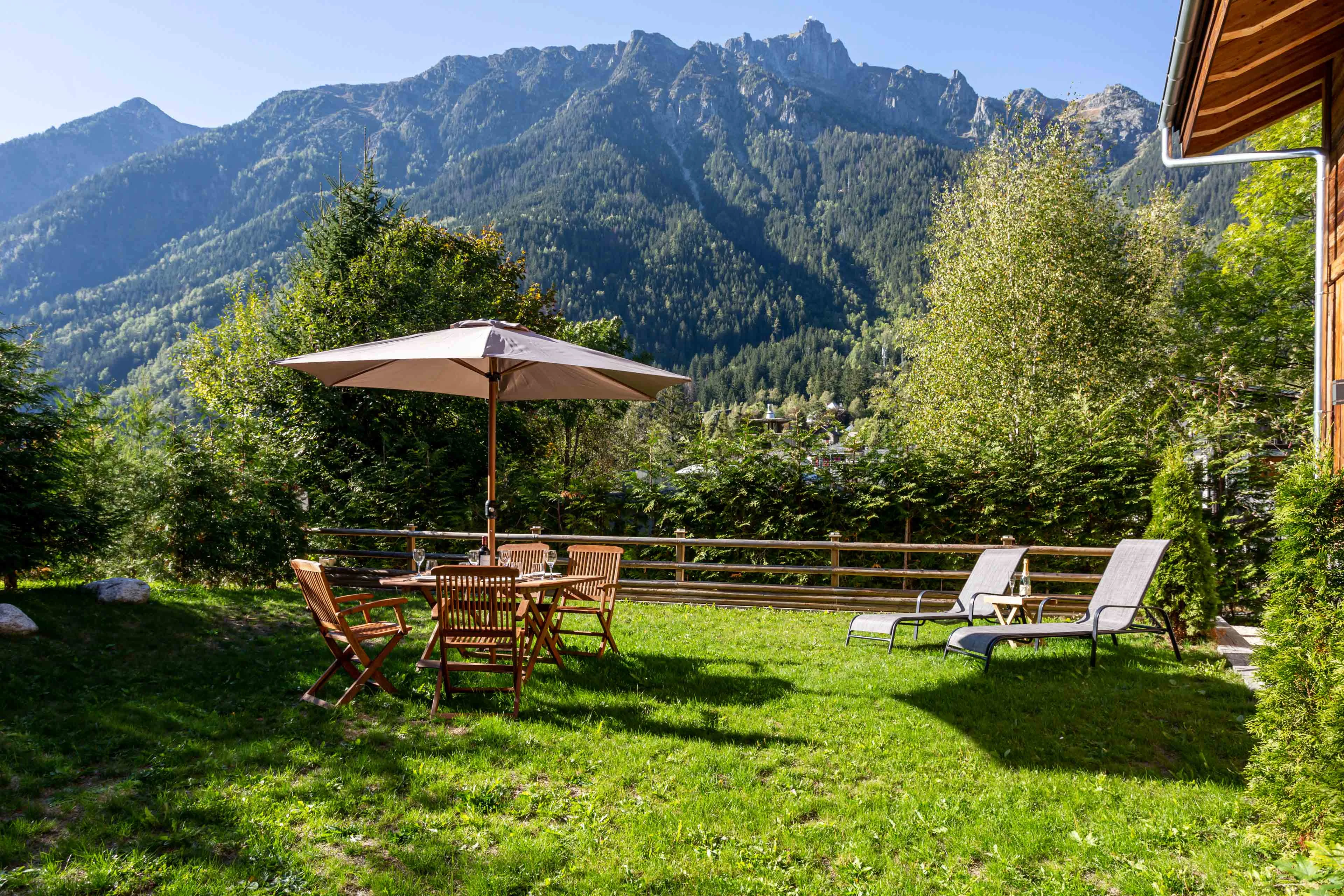 Jardin de chalet à Chamonix avec table, parasol et transats face aux Aiguilles Rouges