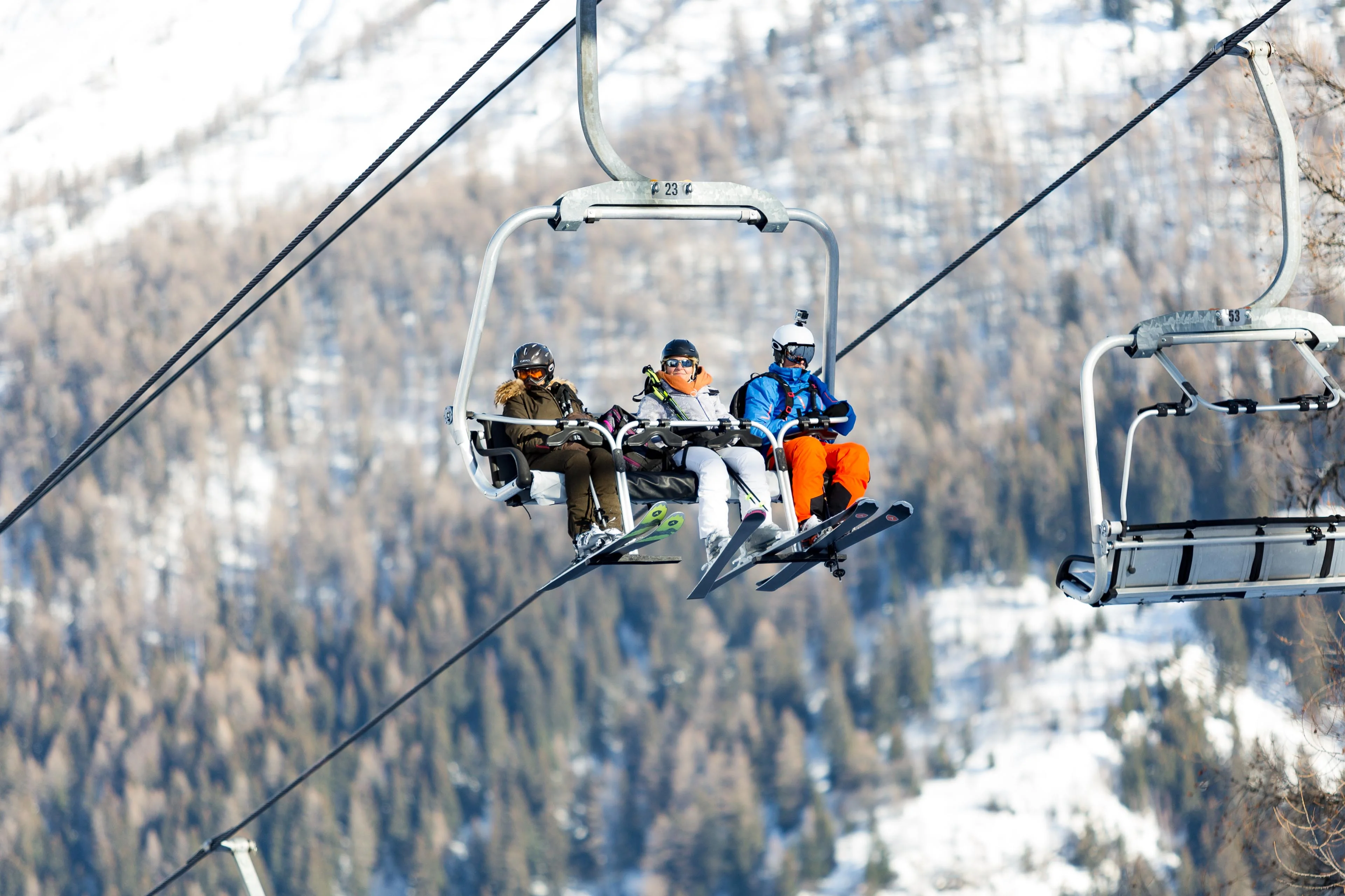 Trois skieurs sur un télésiège au-dessus de la forêt de mélèzes à Chamonix