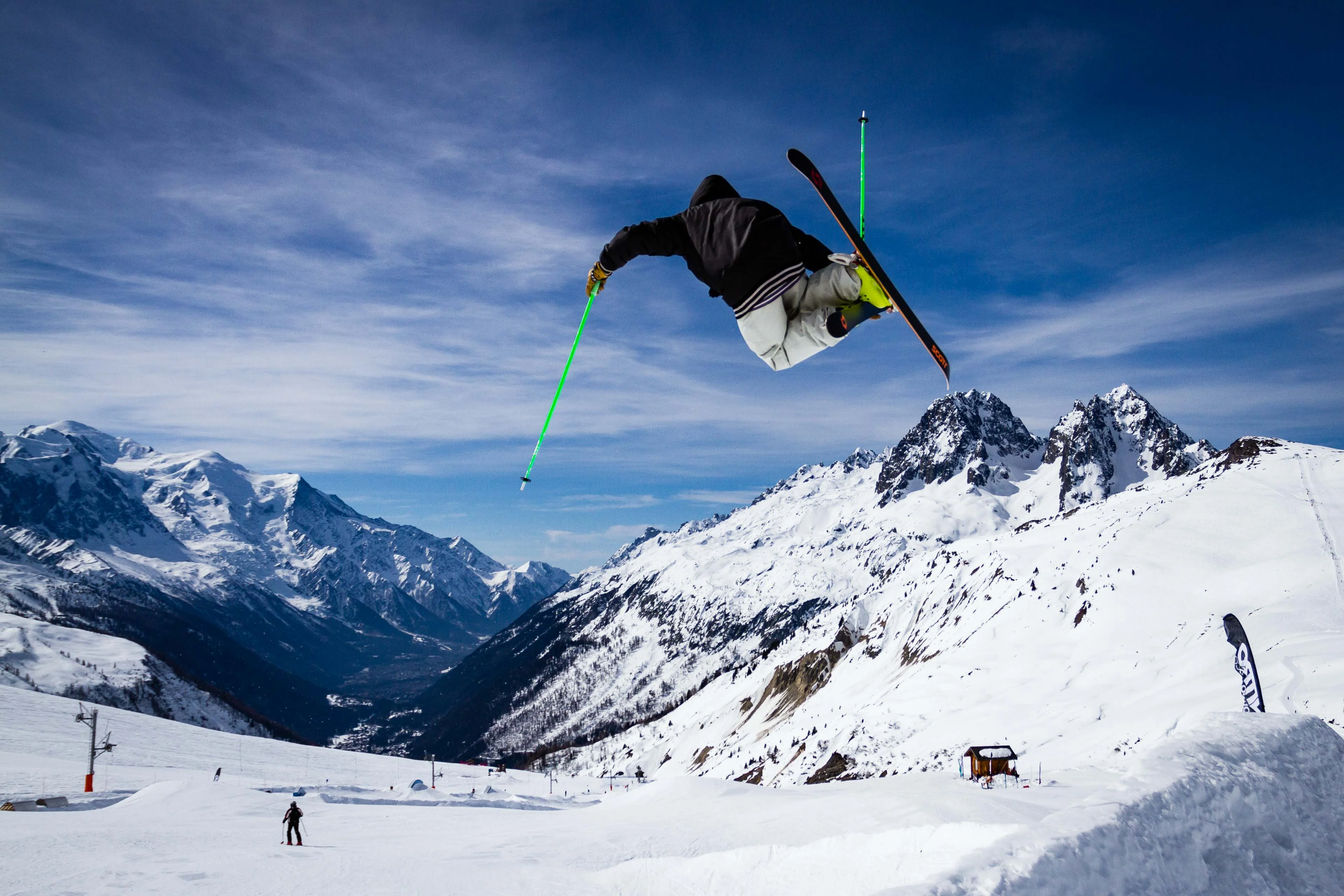 Freestyle skier upside down over a snowpark jump in Chamonix, with the valley below