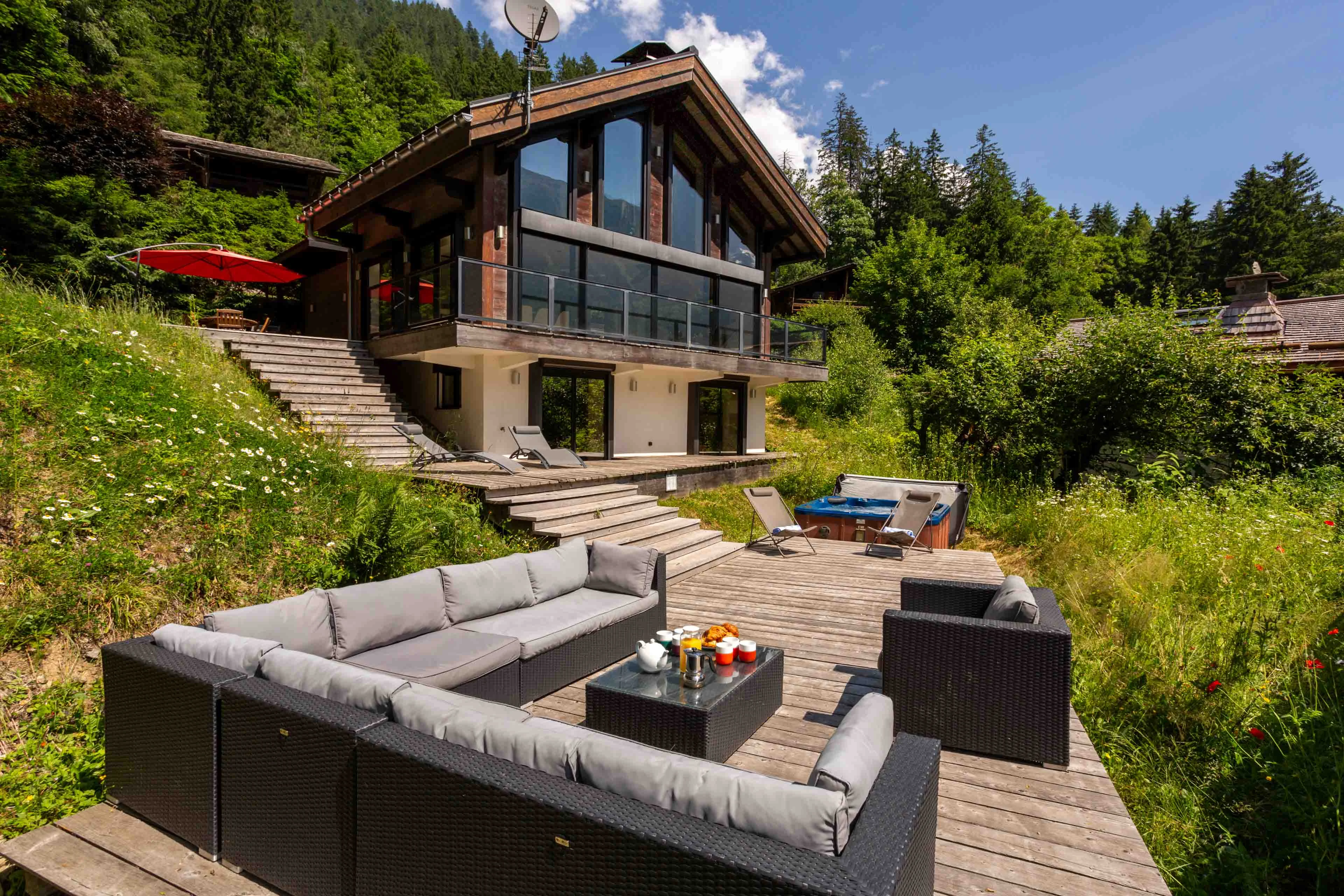 Chalet à Chamonix avec terrasses en bois, salon extérieur et bain à remous dans le jardin en été