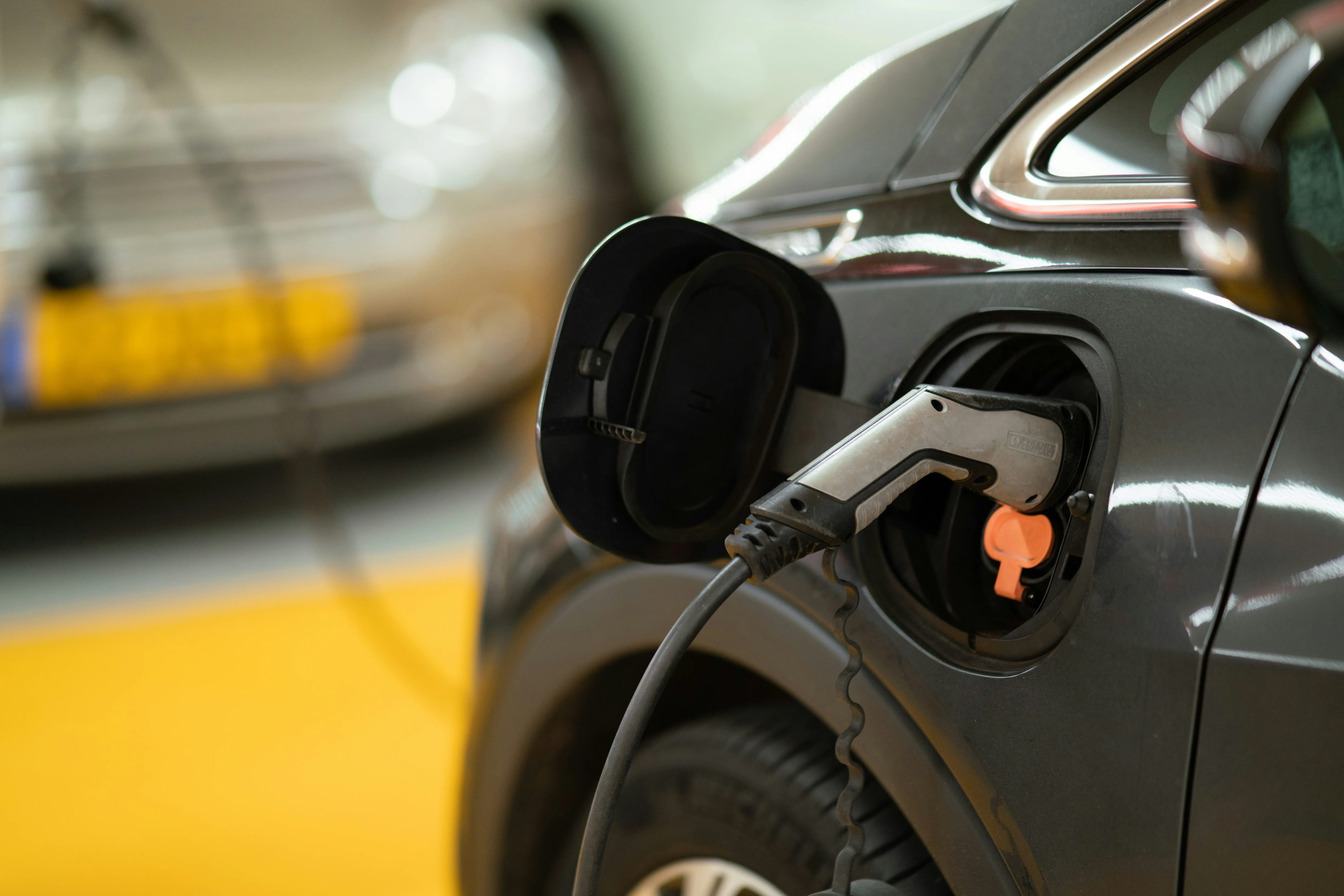 Câble de recharge branché sur une voiture électrique grise dans un parking souterrain