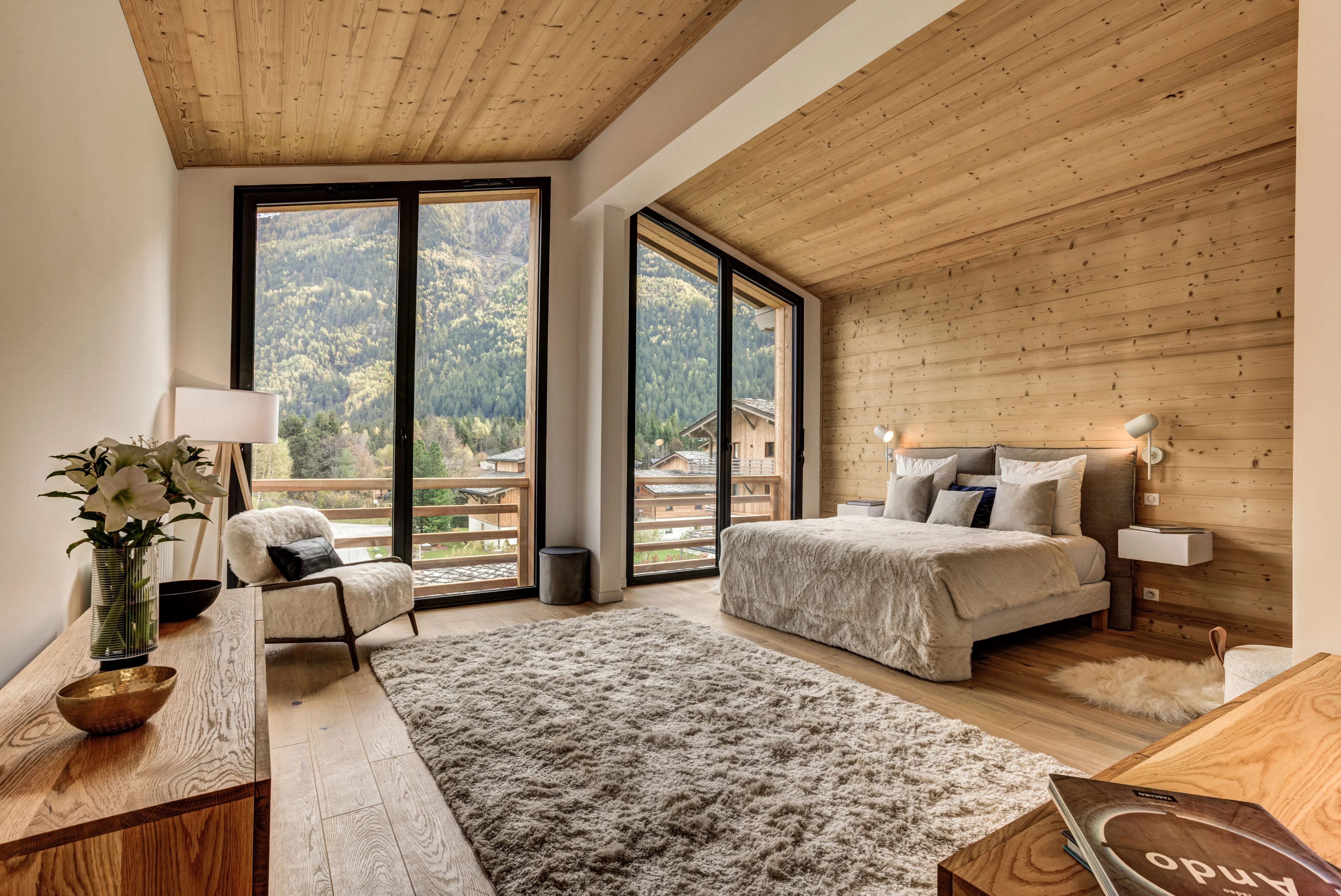 Apartment bedroom in Chamonix with timber walls and floor to ceiling windows onto the mountainside