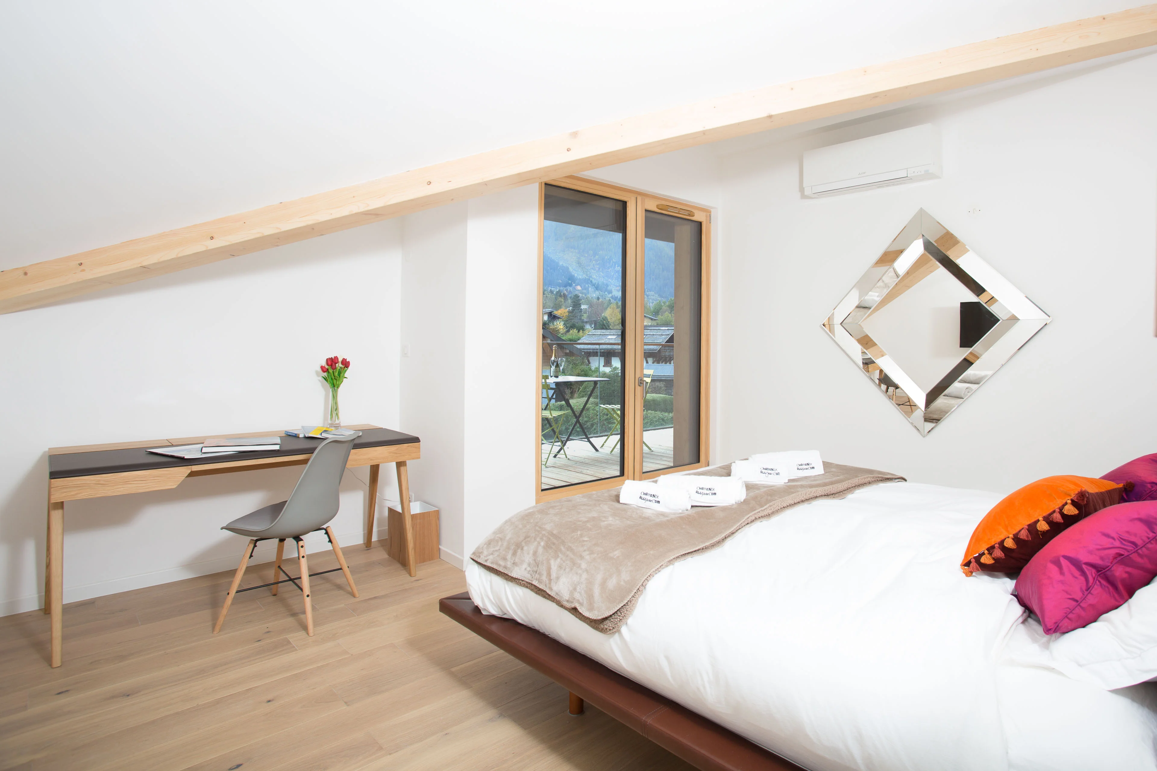 Chambre d’un appartement à Chamonix avec bureau sous les combles et balcon donnant sur les montagnes