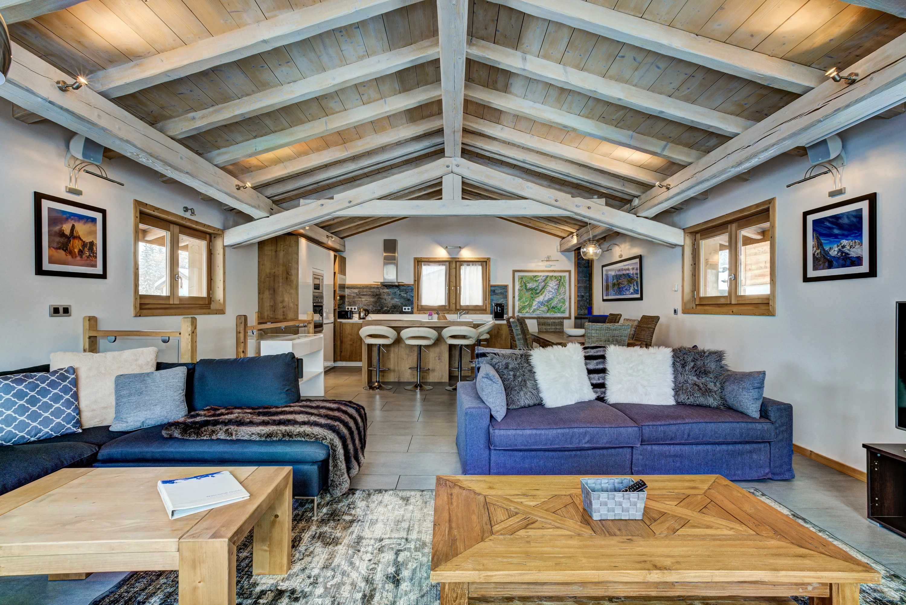 Salon et cuisine ouverts dans un chalet à Chamonix, avec charpente apparente et deux canapés