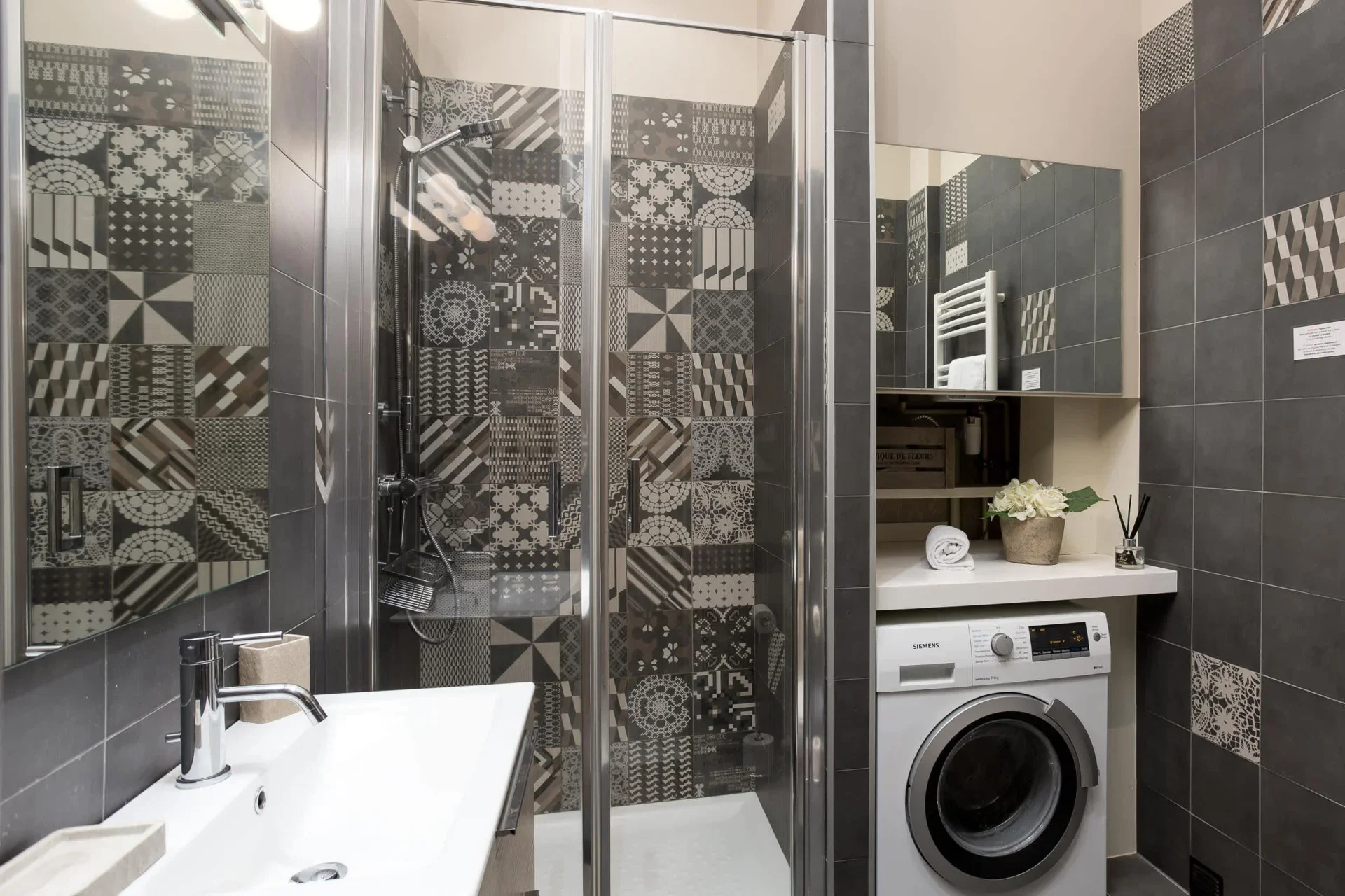 Salle d’eau dans un appartement à Chamonix avec carrelage gris à motifs et lave-linge à côté de la douche