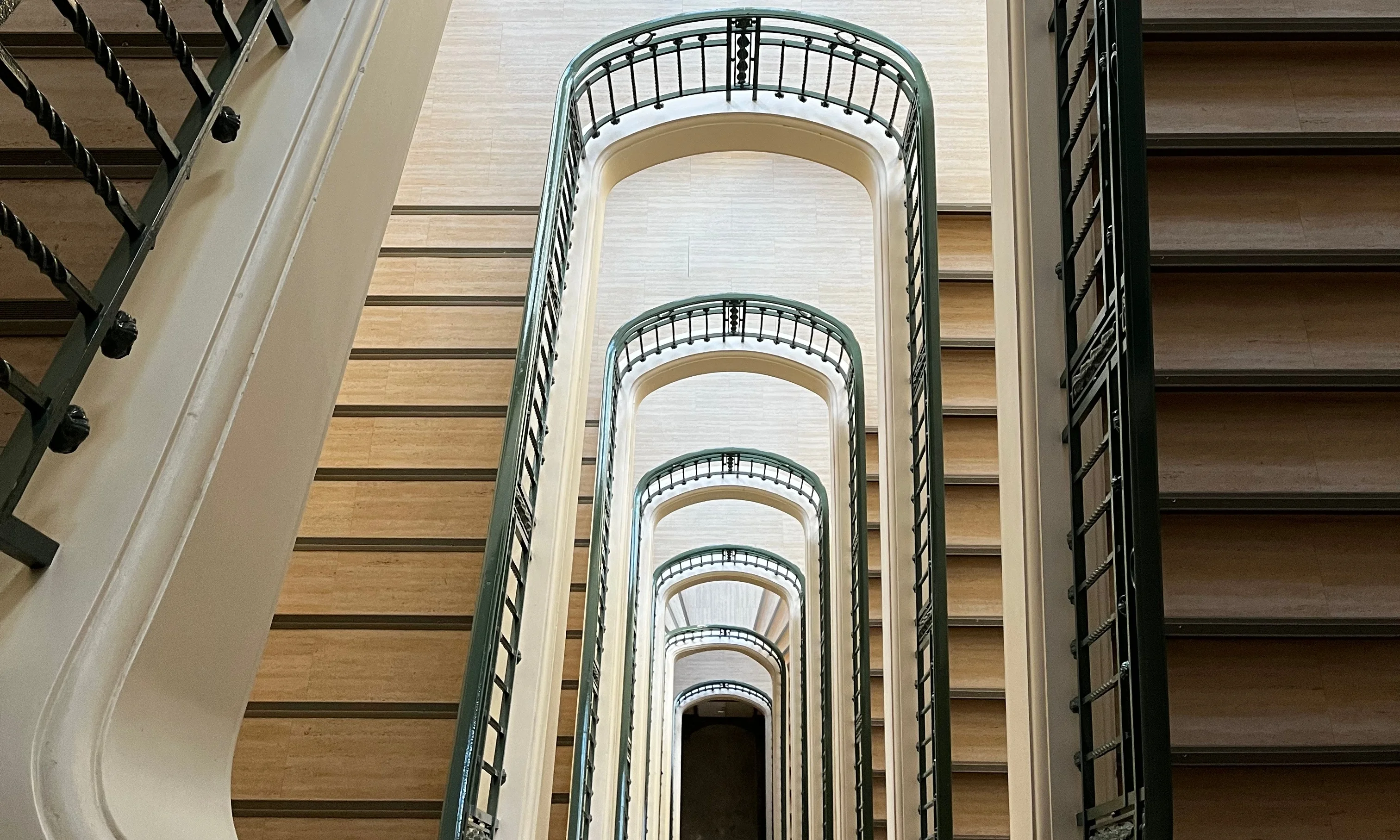 Cage d’escalier d’origine avec rampes en fer forgé dans un bâtiment historique à Chamonix, vue en contre-plongée