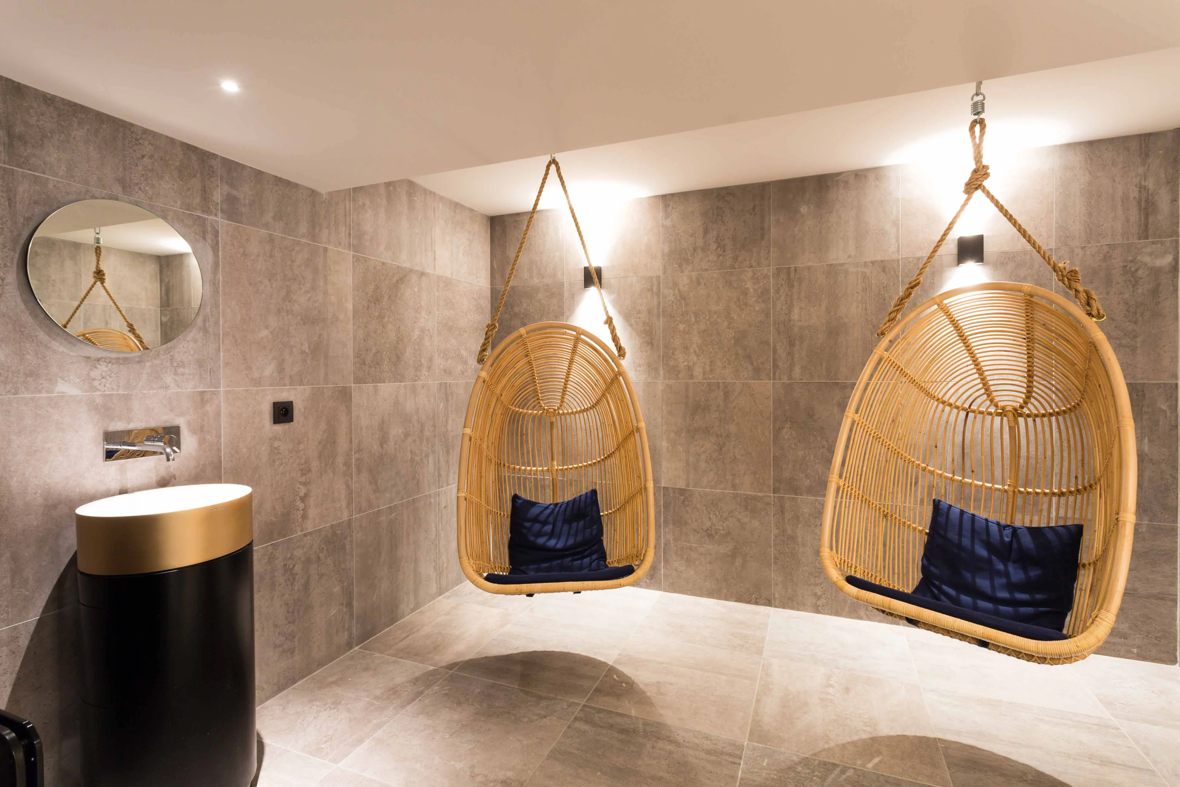 Relaxation area in a Chamonix spa with hanging rattan chairs and stone tiled walls