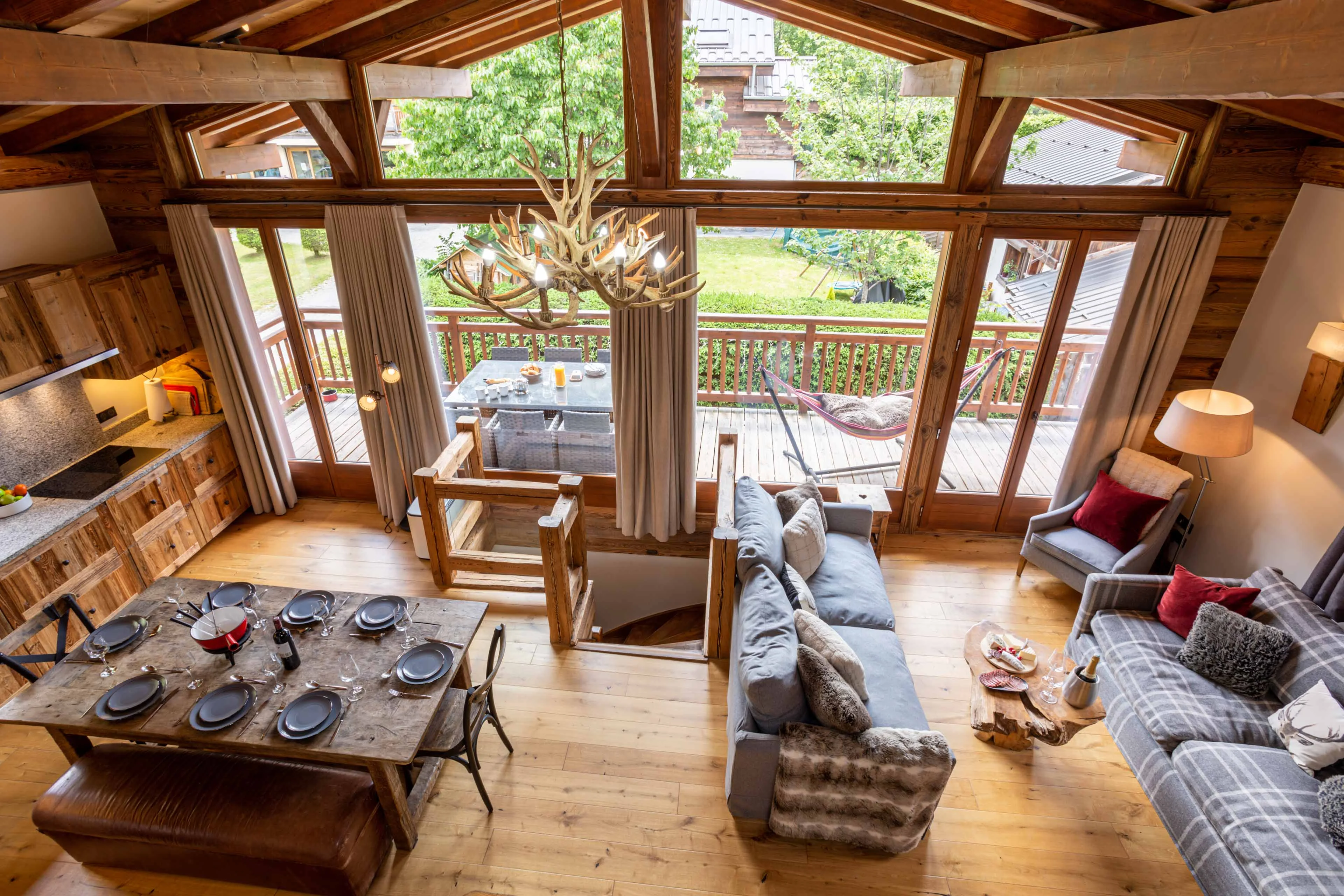 Chalet living and dining room in Chamonix with an antler chandelier, a table laid for eight and doors onto the terrace