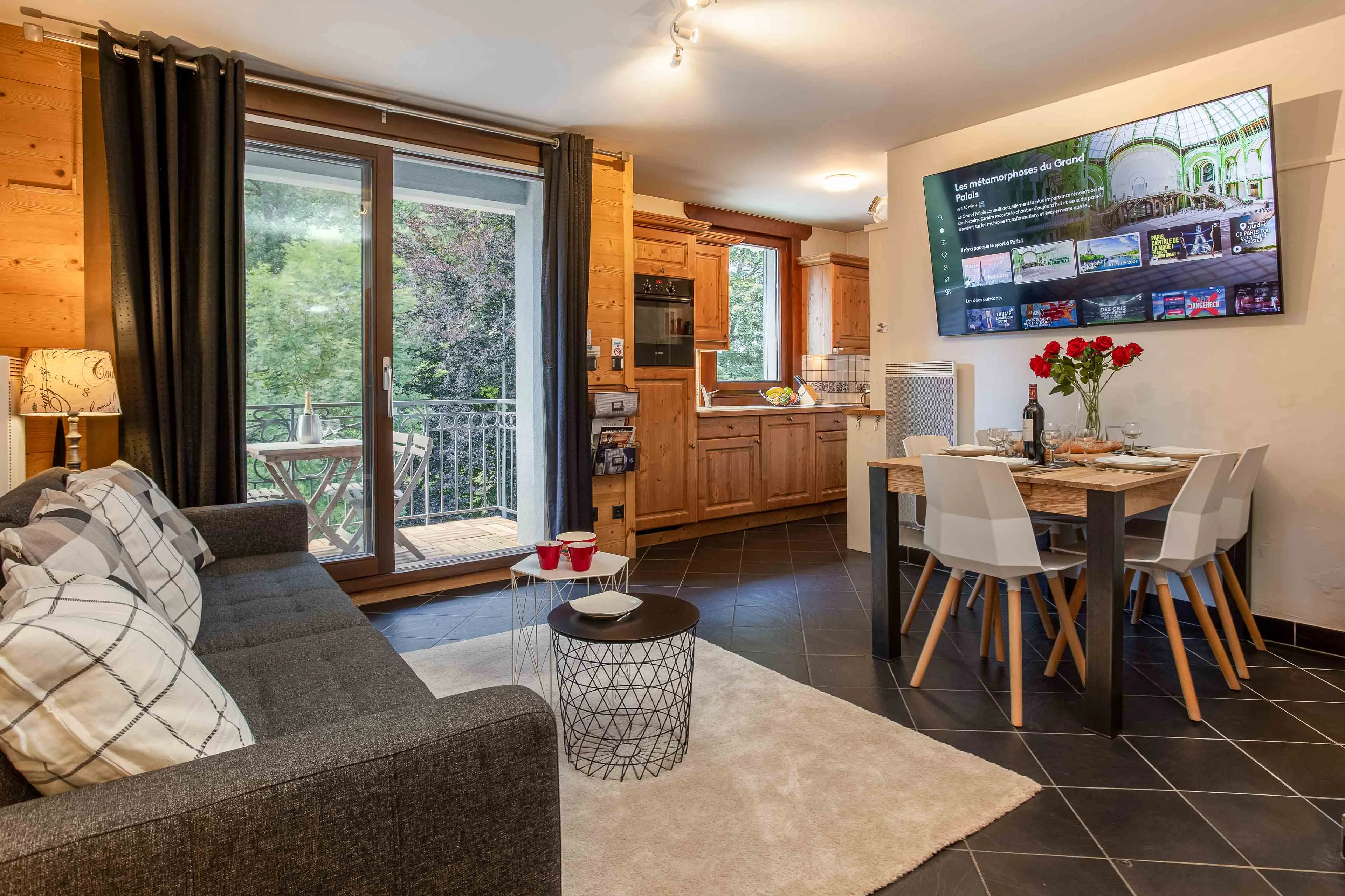 Open plan living room, kitchen and dining table in a Chamonix apartment, with doors onto a balcony