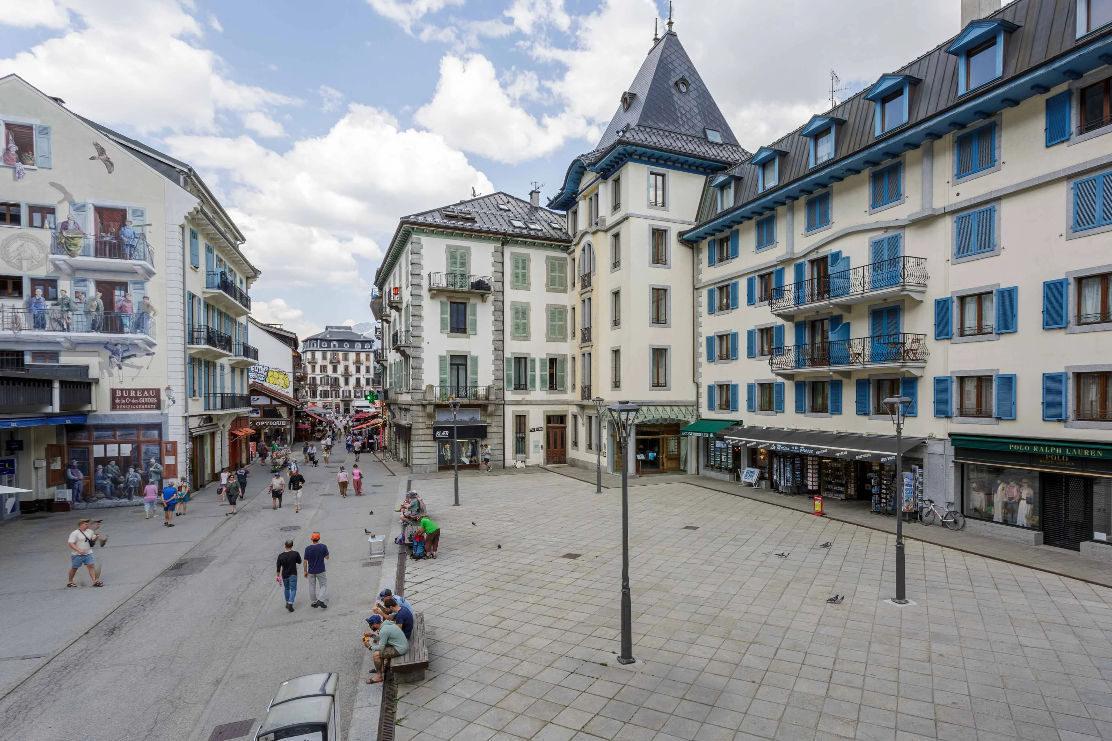 Pedestrian street and square in Chamonix in summer, with shops and the Compagnie des Guides mural
