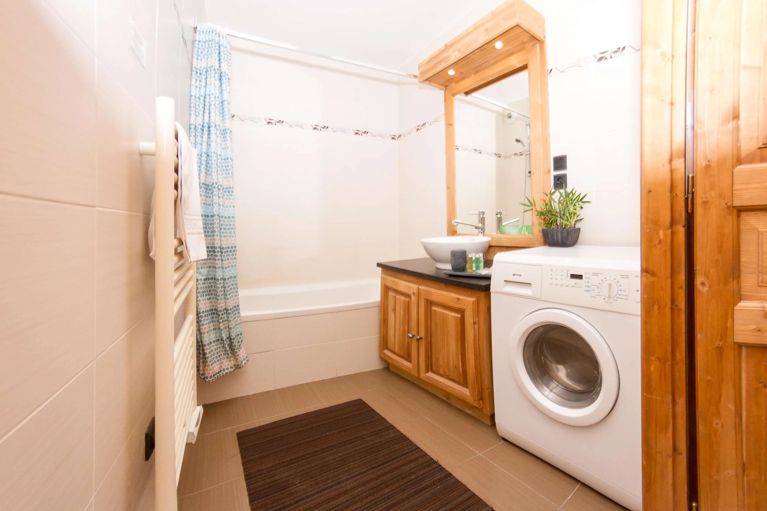 Family bathroom with bath, shower attachment, and washing machine